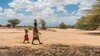 A woman and child walking and carrying water.