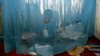 A child sits under a mosquito net in his home.