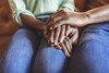 Closeup shot of two unrecognisable people holding hands while sitting on sofa