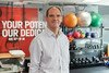 A smiling white man in a white and grey striped shirt in a gym.